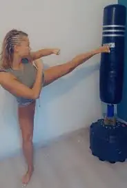 Pratiquante réalisant un coup de pied sur un sac de frappe
