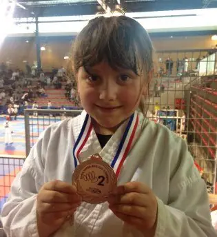Jeune karatéka du Budokai Brive présentant sa médaille